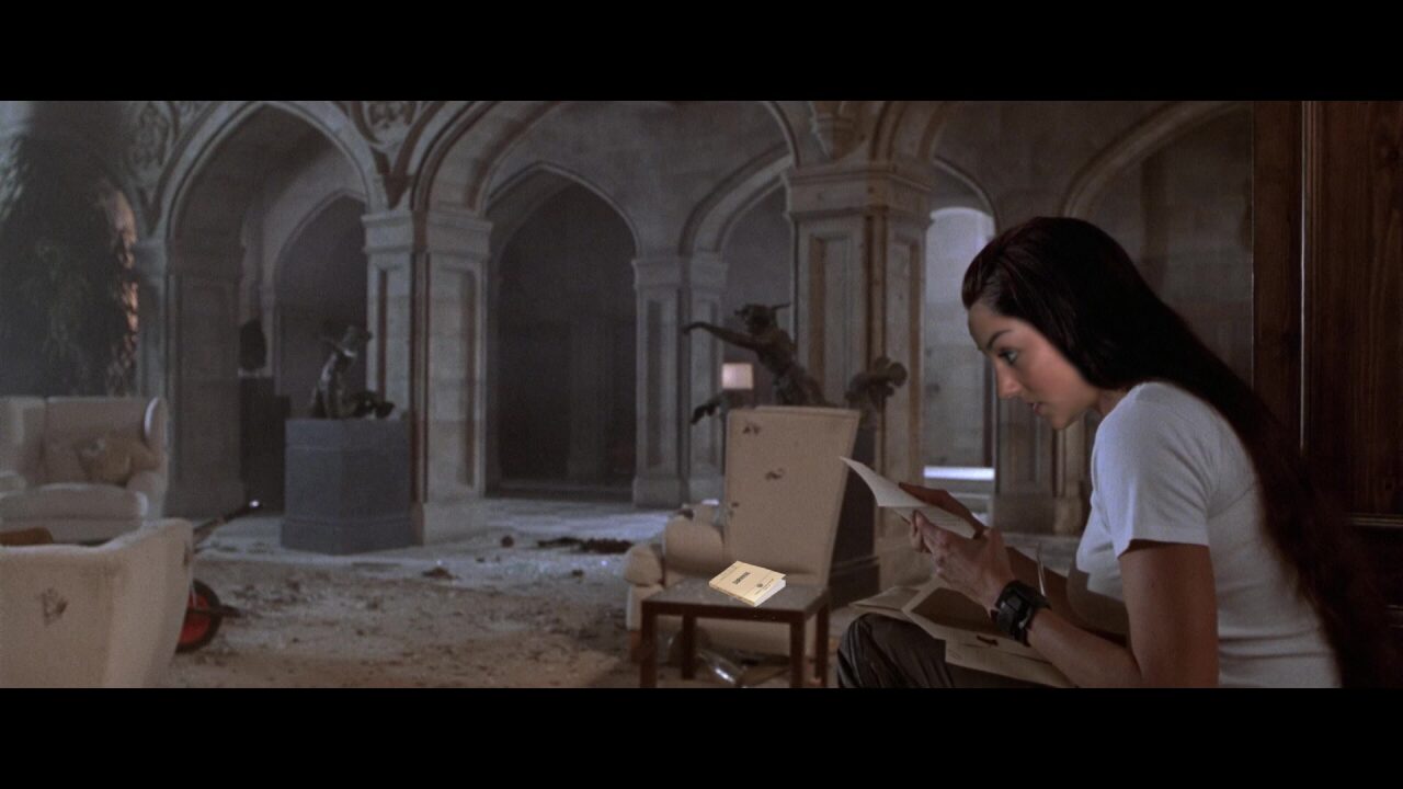 Riley Croft stares intently at a letter, making it seem like she is having a hard time reading and it's actually not surprising because it's super dim in this room, but there's also her survival guide on the table with broken glass. 